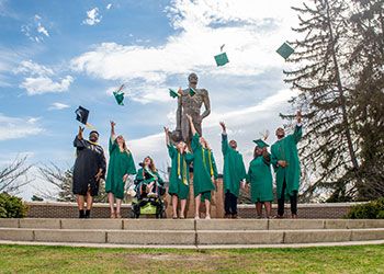 students celebrate graduation at the Spartan statue