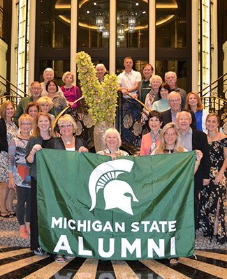 Group of Spartan alumni holding Michigan State Alumni flag 