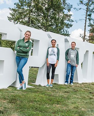 MSU students pose in front of the SPARTANS block text installation