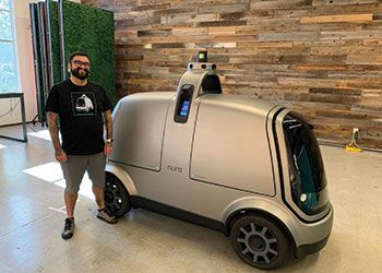 Marshall Mendoza, B.A., '10, Engineering, poses with his company's autonomous vehicle