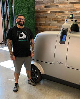 Marshall Mendoza, B.A., '10, Engineering, poses with his company's autonomous vehicle