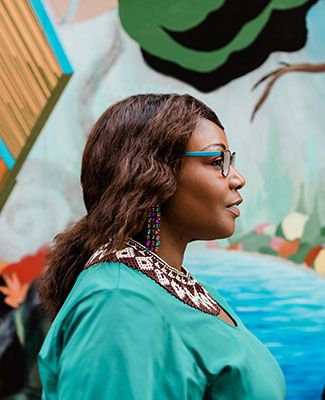 kinitra brooks posed in profile in front of a colorful mural