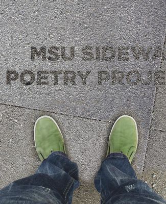 person with green shoes looking down at sidewalk poetry decal.