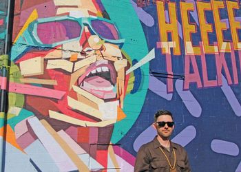 Dustin Hunt stands in front of his Stevie Wonder mural