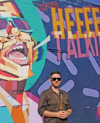 Dustin Hunt stands in front of his mural