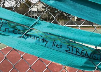 Teal ribbon  on a chain link fence with a message 