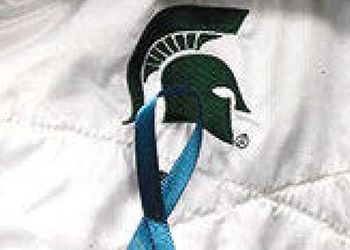 teal ribbon pinned to a jacket with a spartan logo