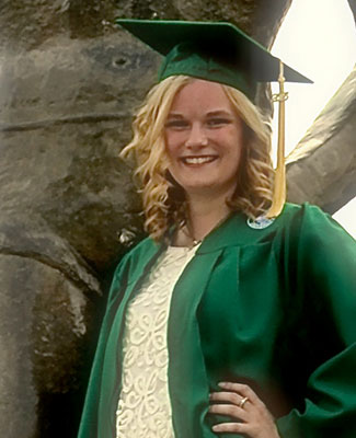 Paulina Schmidtke in her graduation cap and gown, smiles for a photo at the Spartan Statue.