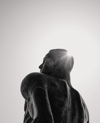 Spartan statue with sun rising over shoulder