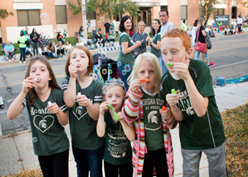 Children blowing bubbles at the MSU Homecoming Parade