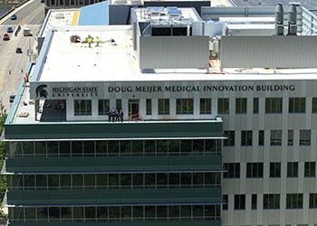 Norm Beauchamp, Doug Meijer, and other stakeholders stand on the roof deck of the new medical innovation building in downtown grand rapids.