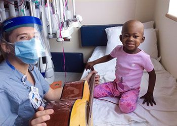 a music therapist sits with a young patient at the Children's Hospital of Michigan