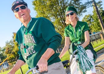 Two Spartans in Spartan gear on a tandem bicycle in the parade