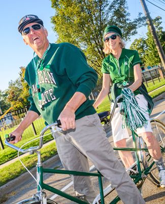 Two Spartans on a tandem bicycle decked out in Spartan gear
