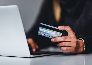 person holding credit card while looking at computer screen