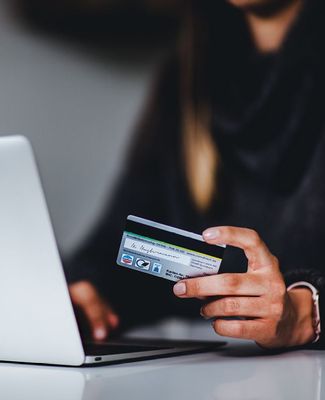 person holding credit card while looking at computer screen