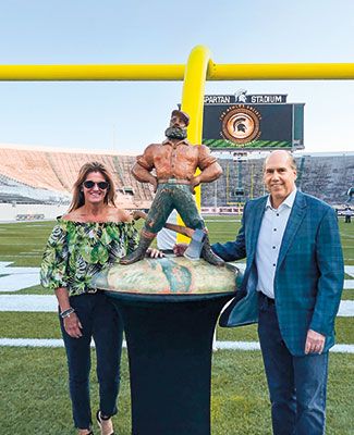 Dawn and Greg Williams posing with the Paul Bunyan Trophy in Spartan Stadium