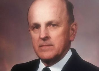 A formal portrait of Dr. Albert Dehn, wearing a dark suit, a white shirt, and a black tie