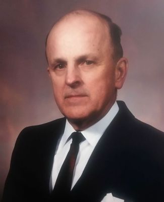 A formal portrait of Dr. Albert Dehn, wearing a dark suit, a white shirt, and a black tie