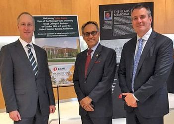 Dressed in dark gray suits, Lear executives and alumni Jason Cardew and Ray Scott pose for a photo with Sanjay Gupta, dean of the Eli Broad College of Business.