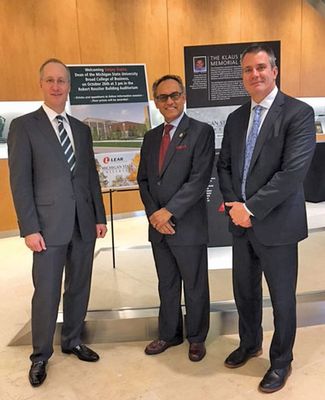 Dressed in dark gray suits, Lear executives and alumni Jason Cardew and Ray Scott pose for a photo with Sanjay Gupta, dean of the Eli Broad College of Business.