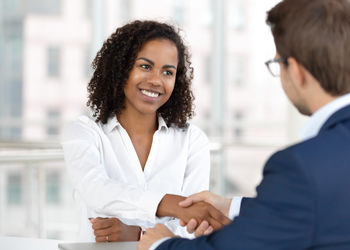 A woman and a man shake hands at a job interview