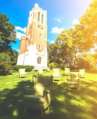 a bunch of empty green armchairs positioned beneath beaumont tower