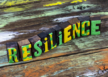 the word resilience is carved out into blocks and the letters are painted green and yellow.