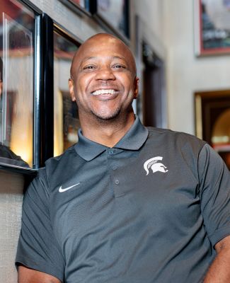 Curtis Daniels III smiles in front of framed records. 