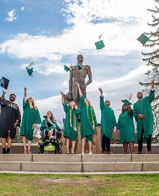 students celebrate graduation at the Spartan statue