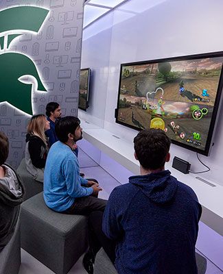 Students play a video game on a large television in the new E sports lounge.
