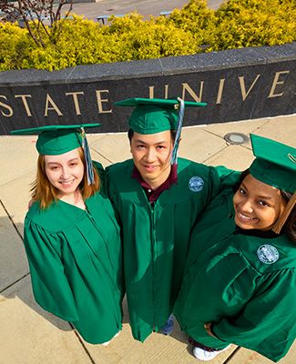 Three MSU graduates smiling, looking up at the camera.