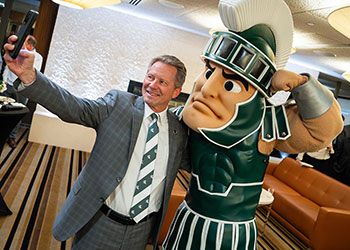 President Kevin Guskiewicz poses for a selfie with Sparty.