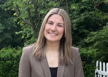 Headshot of Mia Alton in a brown blazer