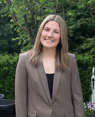 Headshot of Mia Alton in a brown blazer