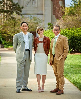 John Jiang, Karen Perry, and Rafael Auras, pose on the sidewalk, with Beaumont Tower in the background.