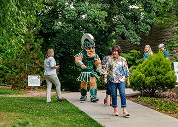 A group of people embark on a nature walk with Sparty