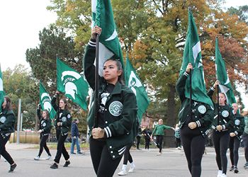 This image shows members of the Spartan Marching Band participating in the Michigan State University Homecoming Parade. 