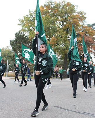 This image shows members of the Spartan Marching Band participating in the Michigan State University Homecoming Parade. 