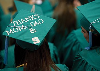 A student wearing an MSU graduation cap that reads, 