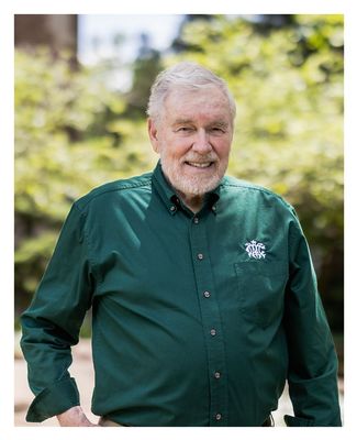 Warren standing outside on campus in a green shirt