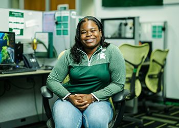 Portrait of Ariel Downs sitting inside the MSU Greenline call center.