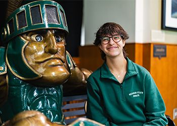 Joanna Gusis sits next to a statue of Sparty.