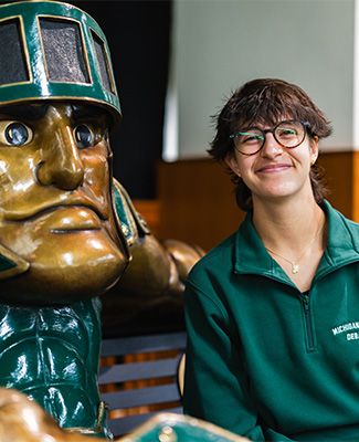 Joanna Gusis sits next to a statue of Sparty.