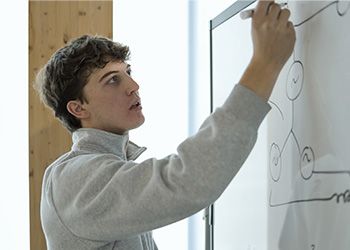 Engineering student Parker Strach solves equations on a whiteboard.