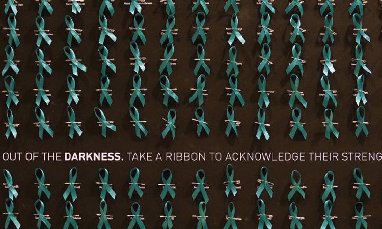 teal ribbons pinned to a black poster