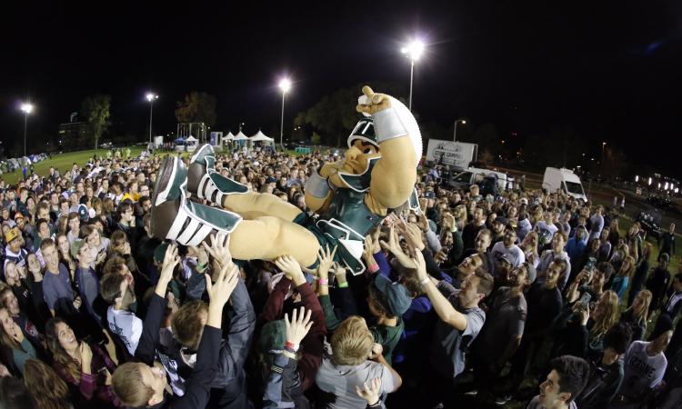 Sparty catches a ride across the crowd.
