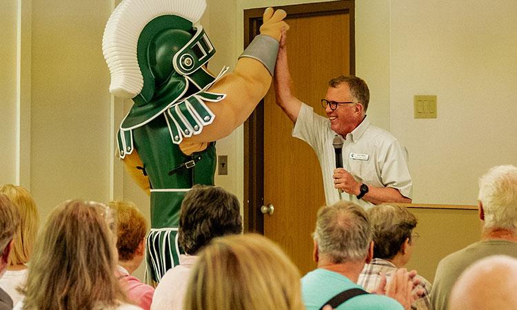 Sparty high-fives a man.