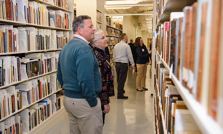 People looking at books on bookshelves.