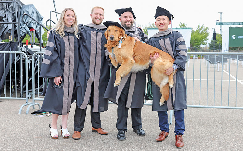 Vet Med grads, with a dog, at graduation